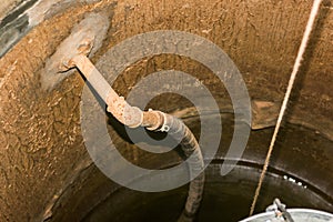 Concrete ring water well with pump and rope with bucket