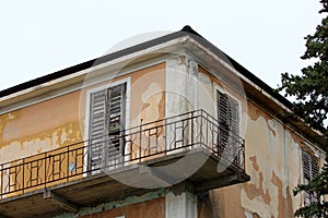 Concrete with rusted metal fence edge balcony on side of old dilapidated abandoned building with cracked facade