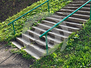 Concrete staircase on a steep slope of green grass