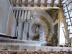 Concrete staircase with wrought iron railings inside an old abandoned house