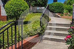 Concrete stairs and curving walkway bordered by brick retaining wall and groundcover