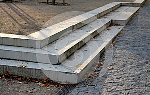 Concrete stairs to the park serving at the same time as a sitting bench. gray cement clean smooth bright cement surface. granite c