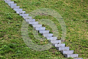 Concrete steps on green grass, stone staircase on a grassy slope