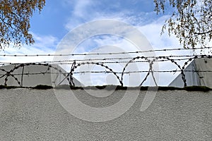 Concrete strong fence with rings of iron sharp barbed wire on top, prison concept, conclusions, bondage