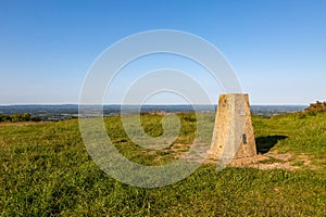 A concrete trig point on Ditchling Beacon with a blue sky overhead