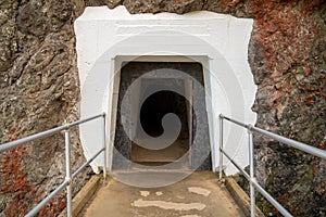 Concrete walking path leading into dark tunnel into mountain side