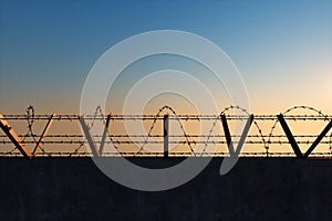 Concrete wall with barbed wire against blue sky. Concept border, prisons, refugees, loneliness. 3D illustration, 3D render, copy
