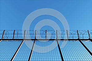 Concrete wall with barbed wire against blue sky. Concept border, prisons, refugees, loneliness. 3D illustration, 3D render, copy