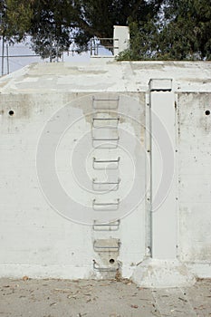 Concrete Wall with Drains and Metal Climbing Ladder photo