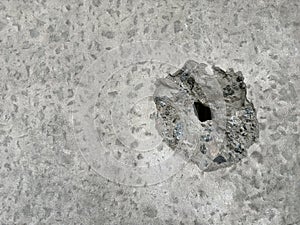 The concrete wall is pierced by a bullet. Background texture: a hole in the concrete from a gunshot. Traces of shelling on the