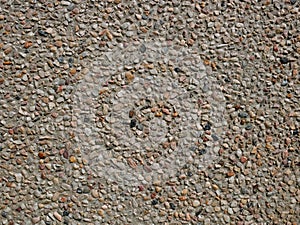 Concrete wall with sandy shapeless stones inlaid into it