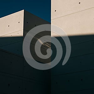 Concrete walls intersect, casting sharp geometric shadows. The surface displays a photo