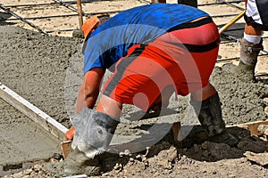 Concrete worker  screeding and leveling the wet mud
