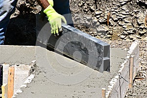 Leveling and smoothing the wet concrete of a garage footing.