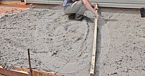 A concrete works construction worker uses special tools to level cement foundation mortar.