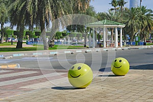 Concrete yellow restrictive spheres with funny smiley face indicating entry to pedestrian zone and park