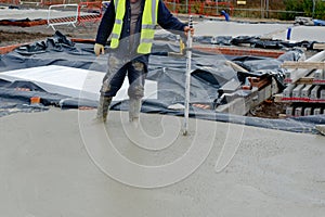 Concreter checking level of the concrete using laser level and staff as he pour ground floor slab of new residential house