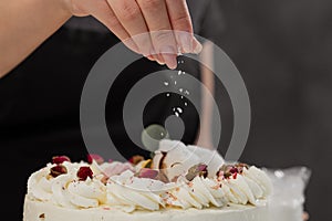 The condater sprinkles the cake with grated almonds and coconut. Close-up of a hand and pouring crumbs.