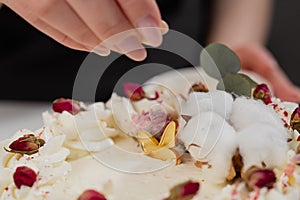 The condater sprinkles the cake with grated almonds and coconut. Close-up of a hand and pouring crumbs.