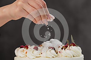 The condater sprinkles the cake with grated almonds and coconut. Close-up of a hand and pouring crumbs.