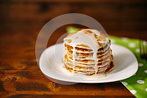 Condenced milk being poured on a stack of pancakes. photo