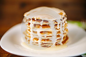 Condenced milk being poured on a stack of pancakes. photo