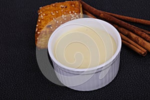 Condenced milk in the bowl with sinnamon and pastry photo