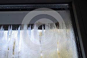 Condensate drops on the glass of a plastic window. Freezing and the formation of condensation and mold on the new