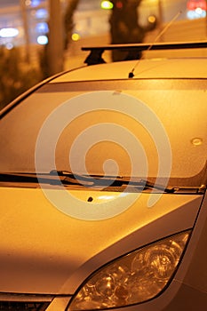 Condensation on a car on a foggy night. Misted car windshield at night. A parked silver car is covered with a wet