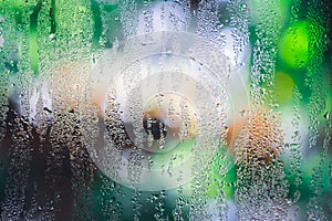 Condensation on the clear glass window with colorful background. Water drops. Rain. Abstract background texture