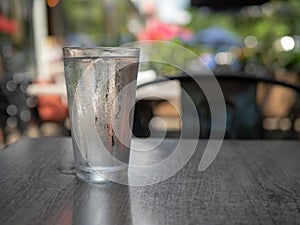 Condensation covered glass of water sitting outside on a dark table photo