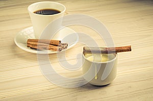 Condensed milk with cinnamon and a white cup with coffee/condensed milk with cinnamon and a white cup with coffee. selective focus