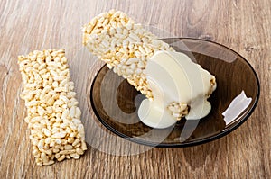 Condensed milk poured on briquette of puffed rice in saucer, puffed rice on table