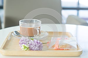 Condensed milk tea or coffee with cookie and flower props is served on wooden tray to customers in the office or car showroom