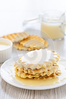 Condensed milk and waffles on a table.