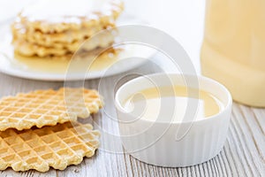 Condensed milk and waffles on a table.