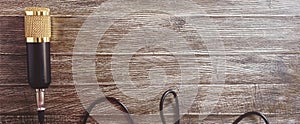 Condenser gold microphone and cable on a wooden table. The light from right side.