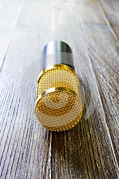 Condenser gold microphone on a wooden table.