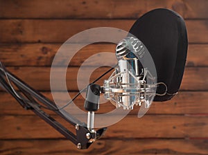 Condenser microphone and pop filter on a wooden background, room for recording podcasts