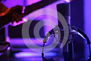 condenser microphone for professional In a recording studio with a guitarist in the background.