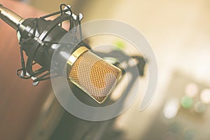 Condenser microphone on a stand attached to a table in a professional recording room