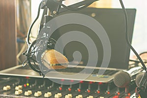 Condenser microphone on a stand attached to a table in a professional recording room