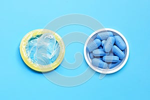 Condom with PrEP ( Pre-Exposure Prophylaxis) used to prevent HIV, in plastic pill bottle cap on blue background. Save sex