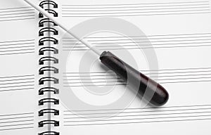 Conductor`s baton on sheet music book , above view photo