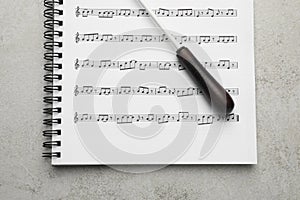 Conductor`s baton and sheet music book on grey background photo