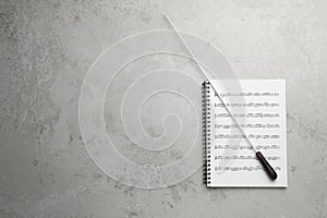 Conductor`s baton and sheet music book on grey background, top view. Space for text photo