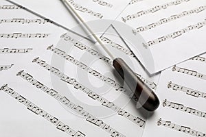 Conductor`s baton on sheet music, closeup view photo