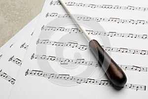 Conductor`s baton and sheet music on grey background photo