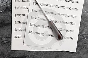 Conductor`s baton and sheet music on grey table, flat lay photo