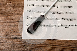 Conductor`s baton and sheet music on wooden table, above view photo